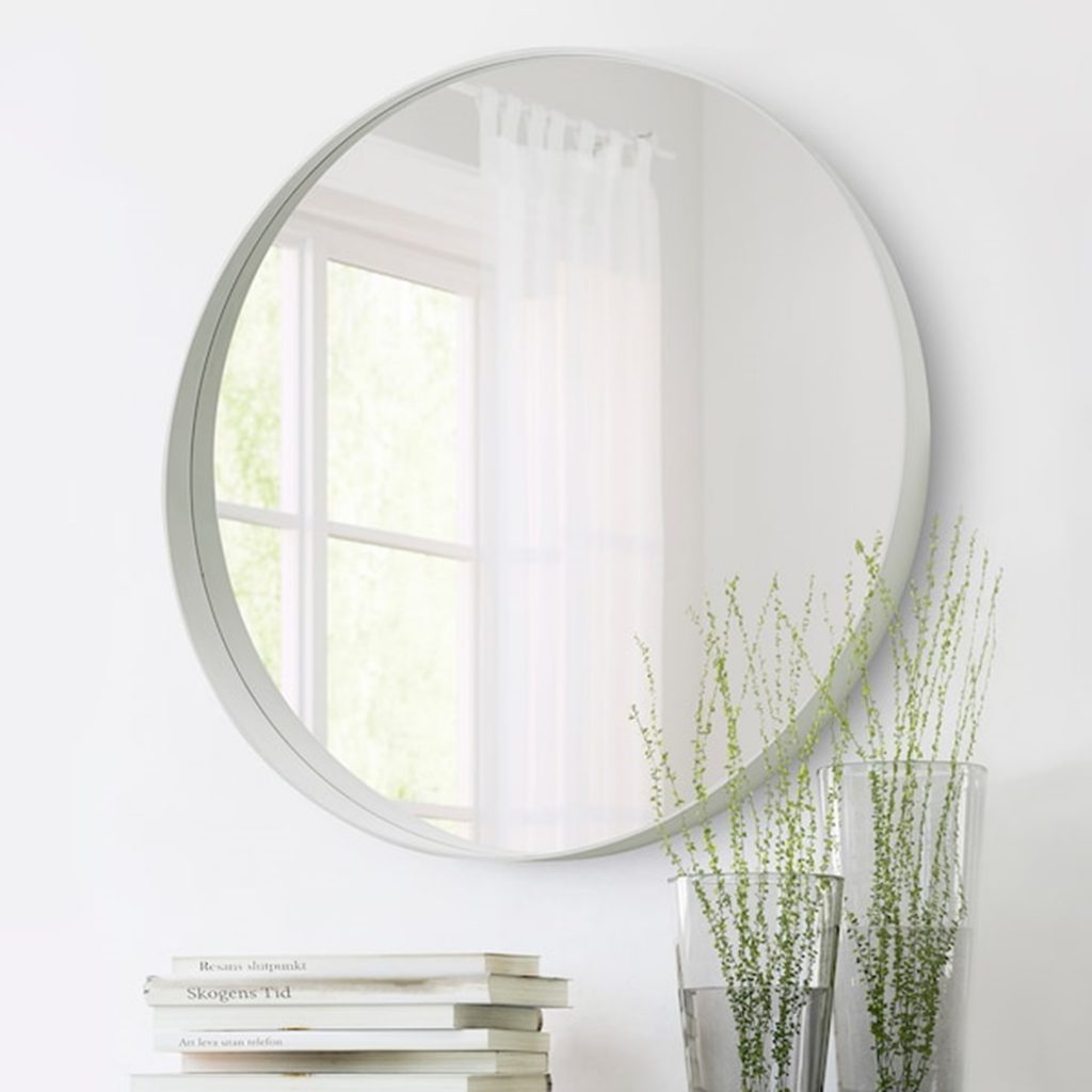 large circular mirror next to plants and books