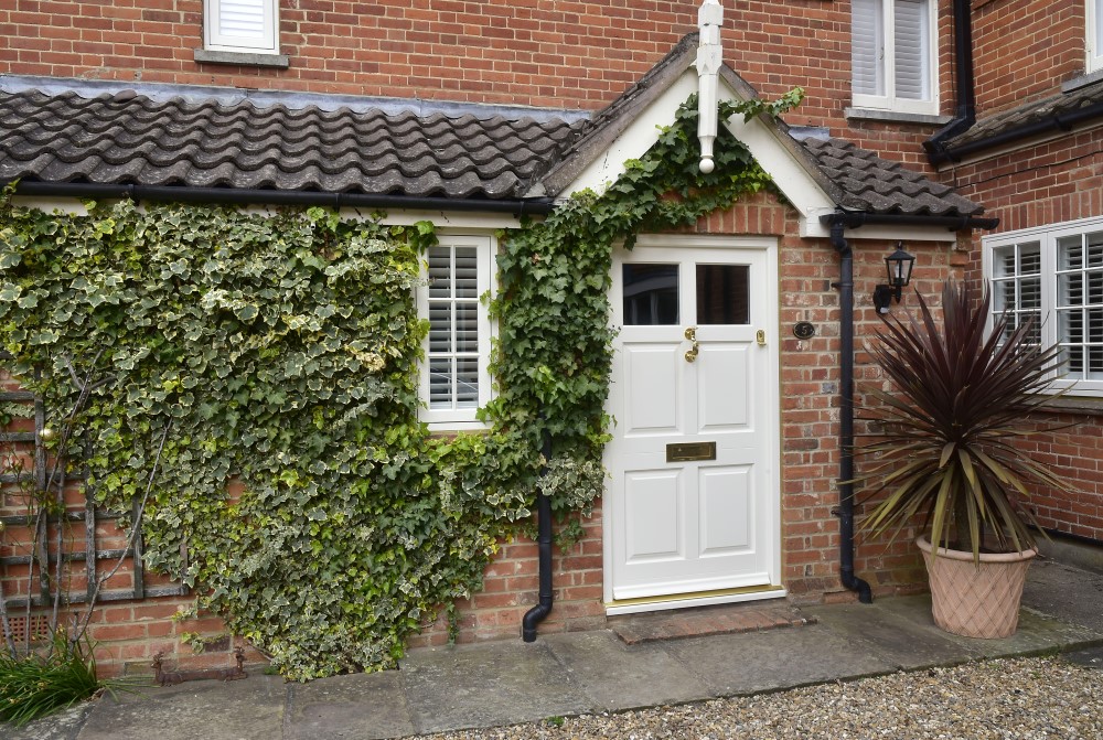 exterior shot of home of home with white door covered in trailing plants