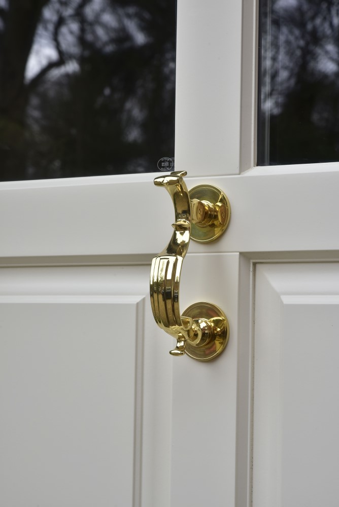 close up shot of brass effect handle on white door