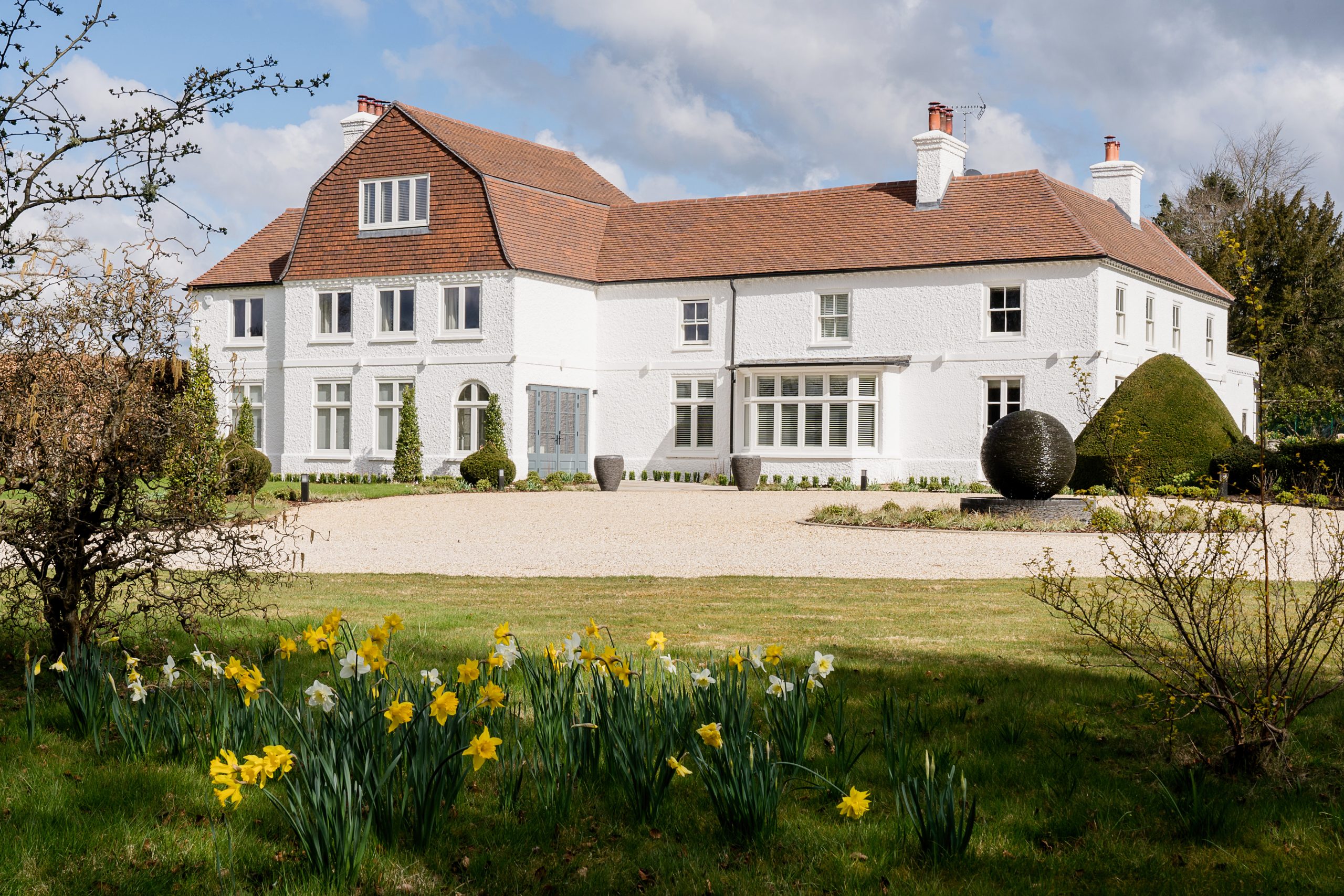 large white country house in background with daffodils in foreground